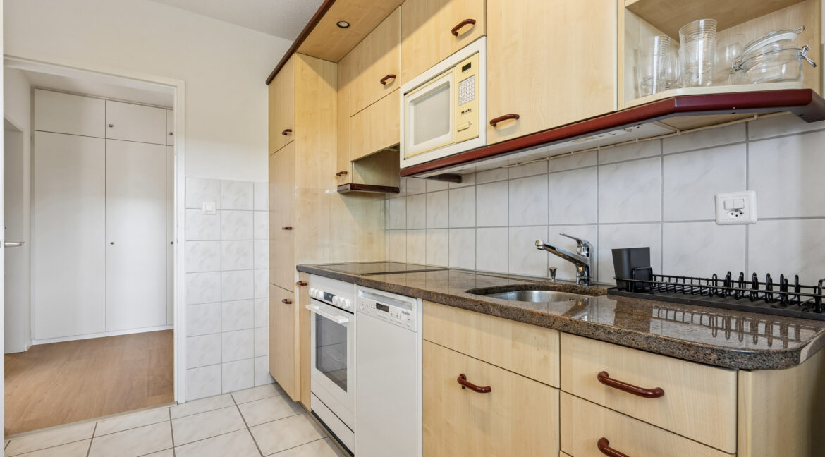 Helle Küche mit Granitabdeckung, Glaskeramik, Kühl- und Gefrierkombination, Geschirrspüler, Mikrowelle und Backofen