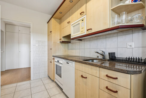 Helle Küche mit Granitabdeckung, Glaskeramik, Kühl- und Gefrierkombination, Geschirrspüler, Mikrowelle und Backofen
